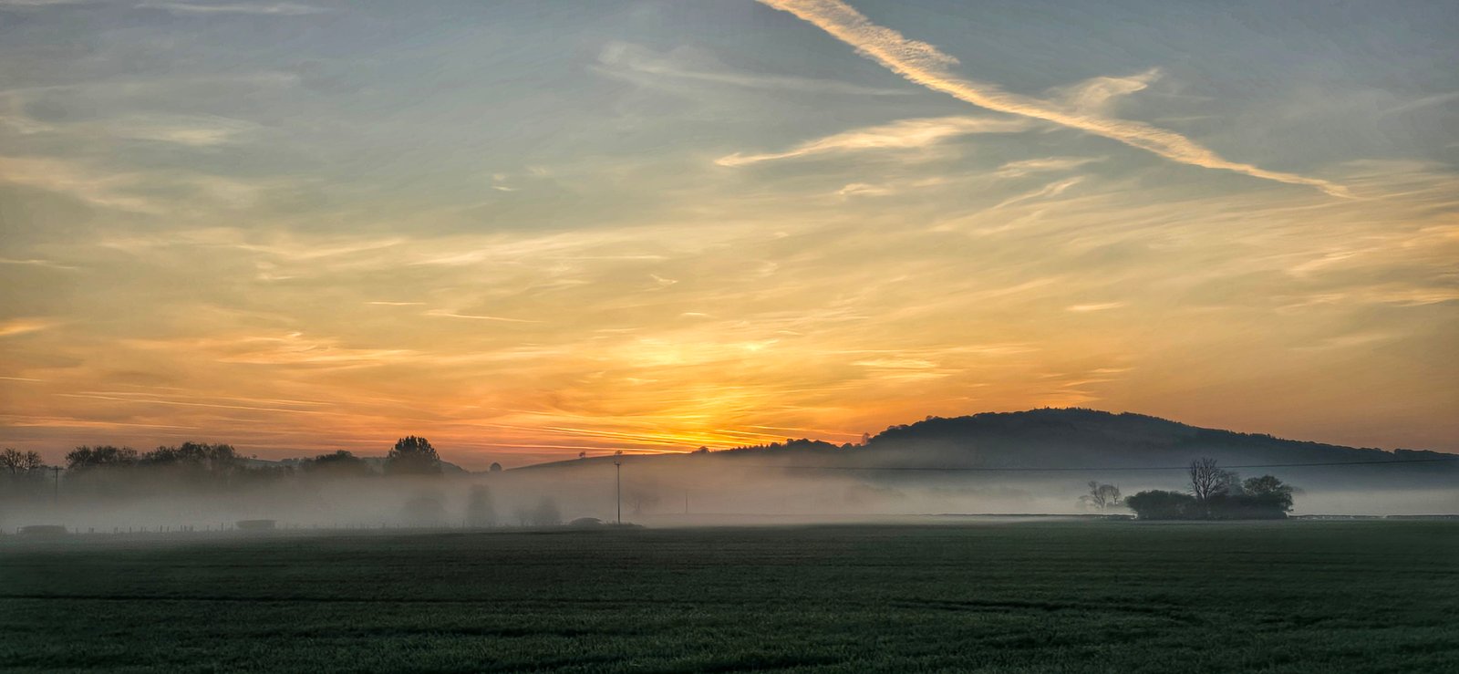Low mist over open fields at sunrise