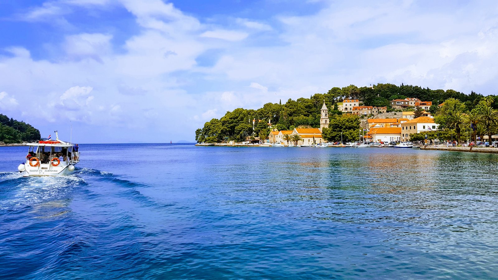 Coastal town and boat wake on deep blue water