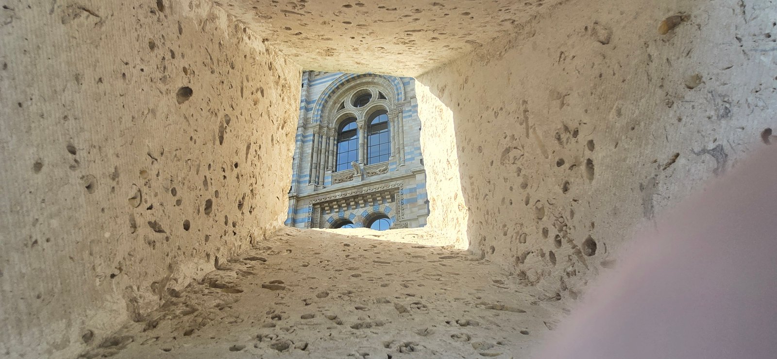 View upward through a stone opening toward ornate architecture